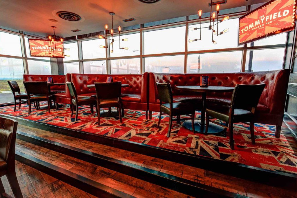 Three booths of red leather surrounded by windows and two TVs.