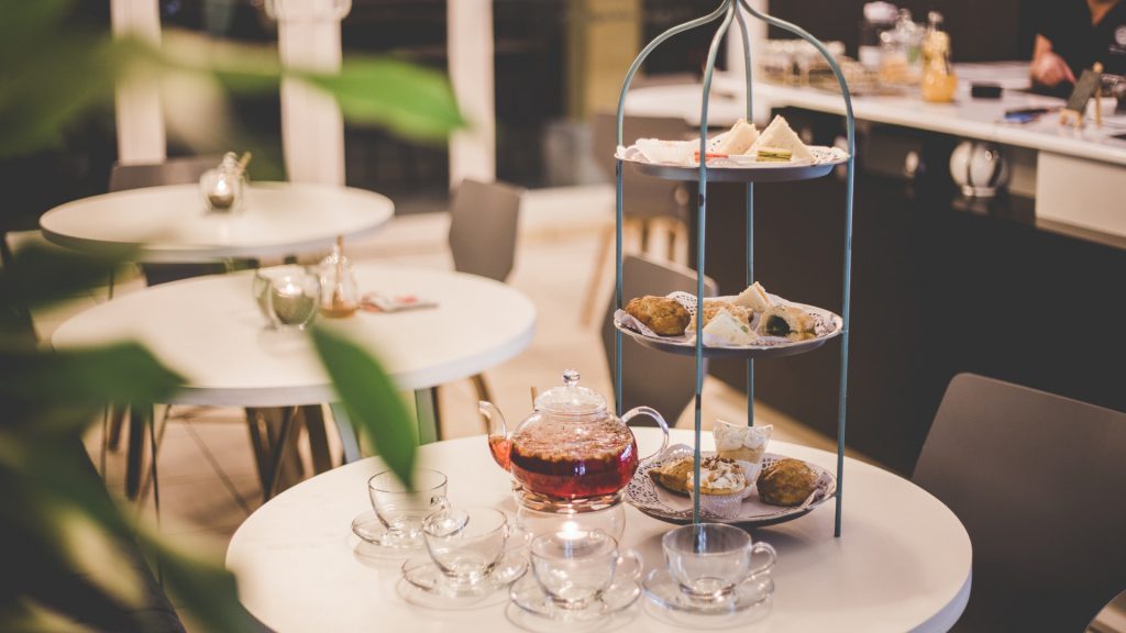 a table set for afternoon tea with fresh tea, pastries, and finger sandwiches