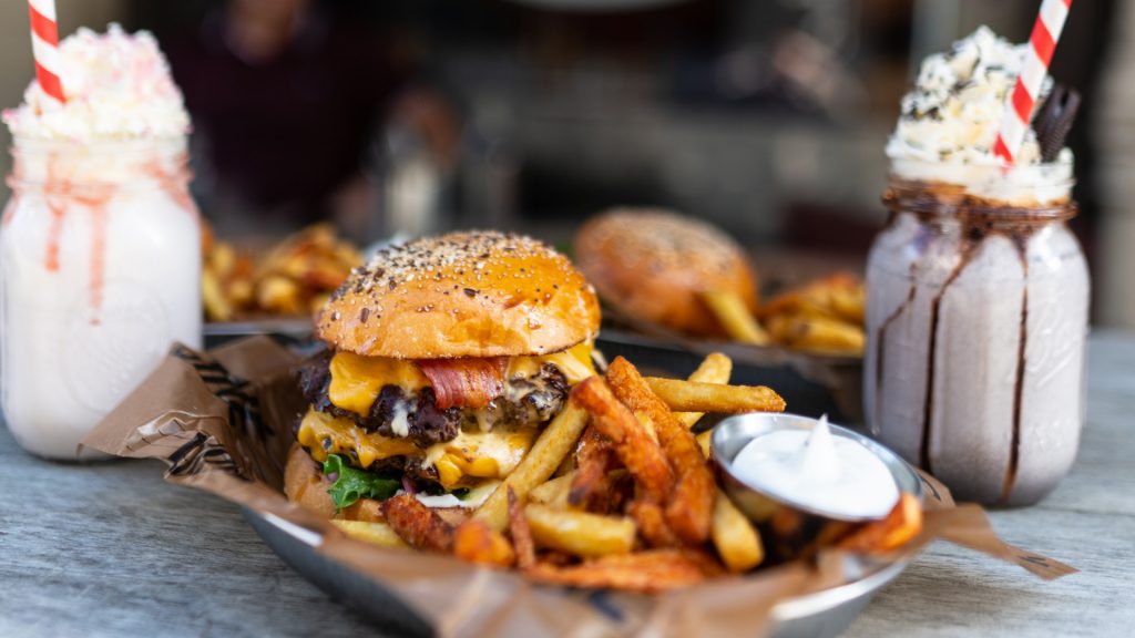 double bacon cheeseburger with fries alongside strawberry and chocolate milkshakes 