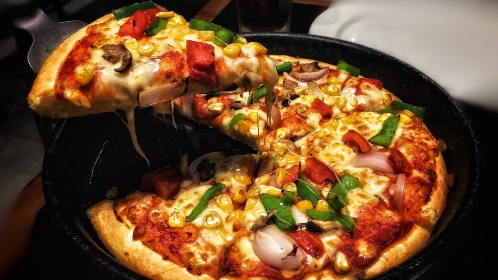 deep dish pizza in a cast iron pan with lots of vegetable toppings