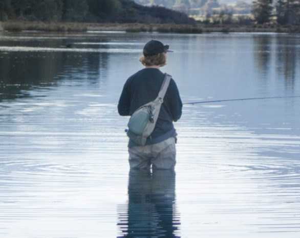 fly fisher standing in the river waiting for a fish to bite