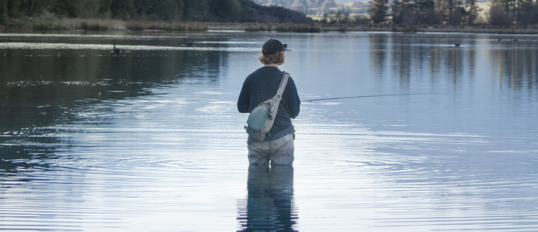 fly fisher standing in the river waiting for a fish to bite