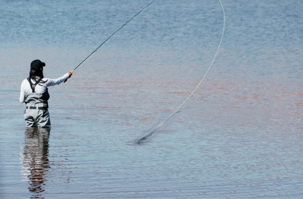 fly fisher casting their line out into the bow river