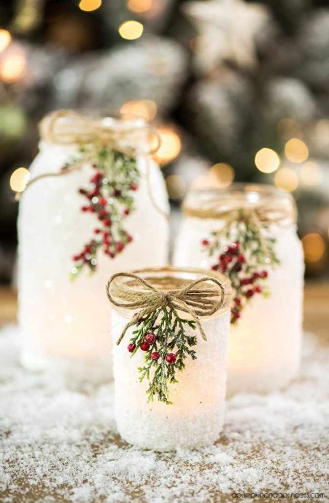 mason jars with greenery, twine, and cranberries that look like they're filled with snow